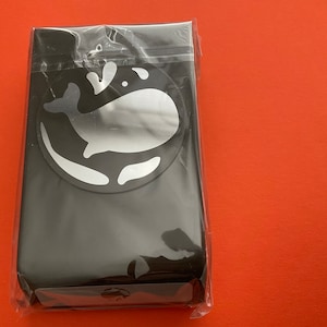 May include: A black package with a clear plastic window. The package has a white whale design with a splash of water.