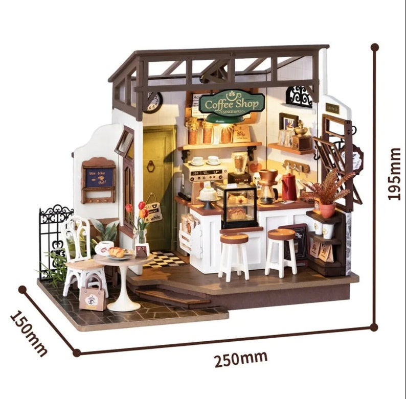 May include: A miniature wooden dollhouse model of a coffee shop with a white exterior, brown roof, and a black and white checkered floor. The shop has a sign that reads "Coffee Shop" and features a small outdoor seating area with two chairs and a table. The dollhouse measures 150mm wide, 250mm deep, and 195mm tall.