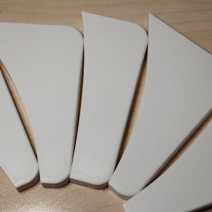 Op de afbeelding: Zes witte plastic driehoeken in een waaier vorm.