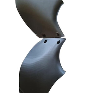 May include: Two gray, curved metal panels, possibly automotive parts, are stacked vertically against a white background. Each panel has a smooth, reflective surface and several small holes. The panels have a unique, aerodynamic shape.