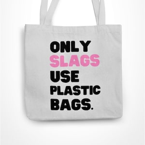 May include: A light grey tote bag with the slogan "ONLY SLAGS USE PLASTIC BAGS" in black and pink lettering. The bag has two white handles and is made of a canvas-like material.