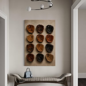 May include: A rectangular wall art print featuring a grid of twelve baseball gloves in various shades of brown and black, arranged in four rows of three. The artwork is displayed above a tufted bench with a handbag and a pair of trainers.