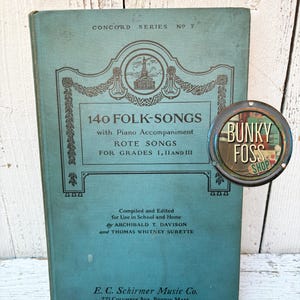 May include: A teal blue book titled "140 Folk-Songs" with piano accompaniment. The book is part of the Concord Series, No. 7. It includes rote songs for grades 1, 2, and 3. The book was compiled and edited by Archibald T. Davison and Thomas Whitney Surette. It was published by E.C. Schirmer Music Co. in Boston, Massachusetts.
