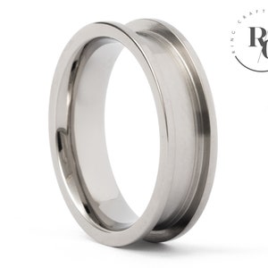May include: A silver-toned metal ring with a wide, flat band and a bevelled edge. The ring is designed to be worn as a spacer ring.