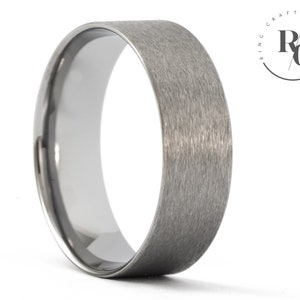 May include: A brushed silver wedding band with a flat profile.