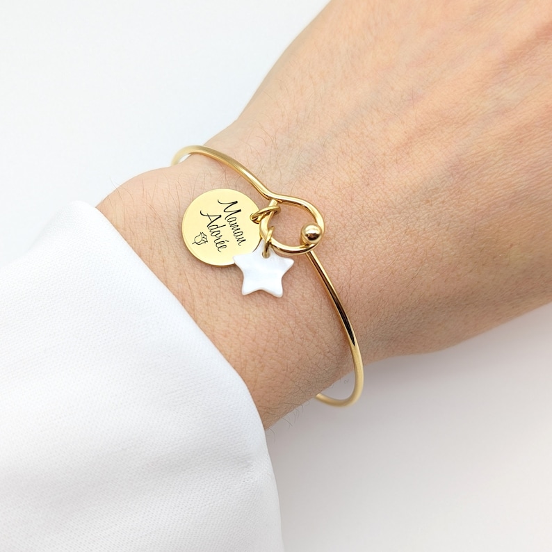 Bracelet jonc en acier inoxydable avec médaille de 15 mm et une médaille nacrée au choix : coeur, étoile ou croix. La médaille peut etre gravée au recto et verso.