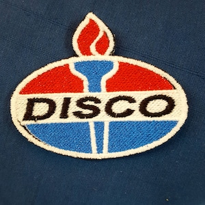 Peut inclure: Patch brodé avec un motif rouge, blanc et bleu. Le patch présente une flamme stylisée et le mot "DISCO" en lettres noires.