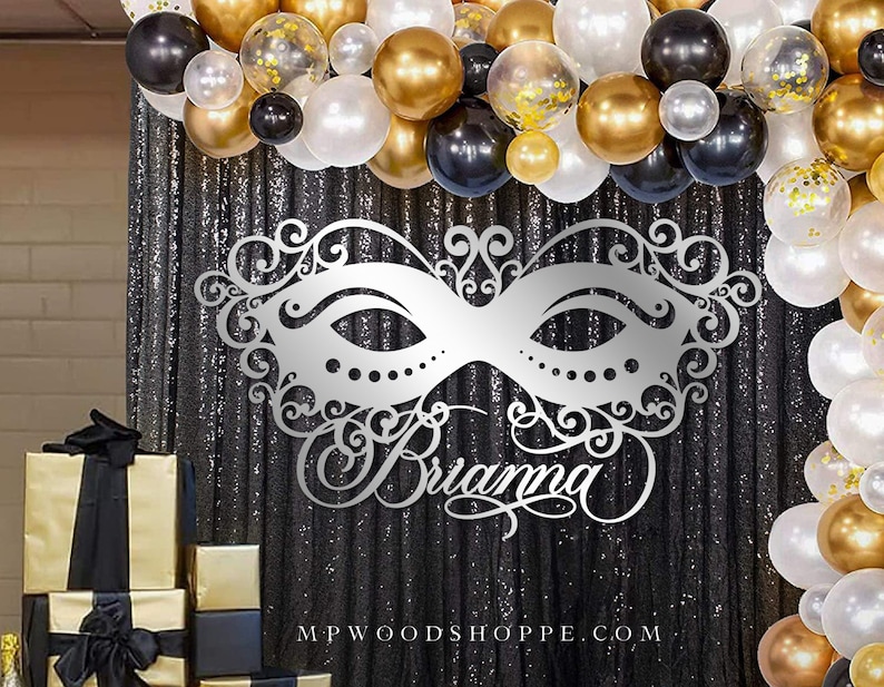 K&ouml;nnte beinhalten: Ein silberner Glitzer-Hintergrund mit einer gro&szlig;en silbernen Glitzermaske und dem Namen "Brianna" in Kursivschrift. Der Hintergrund ist mit einer Girlande aus schwarzen, goldenen und wei&szlig;en Luftballons verziert.