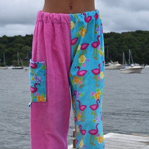 May include: Pink and blue towel pants with a flamingo print on one leg. The pants have a pocket on the pink side.