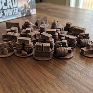 May include: A collection of brown miniature game pieces featuring various supplies including wooden crates, barrels, and barricades. These small, detailed plastic tokens are designed for tabletop gaming and are arranged in a group on a flat surface.