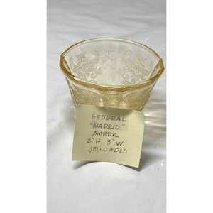 May include: Amber glass "Madrid" jello mold by Federal. The mold is 2 inches tall and 3 inches wide.