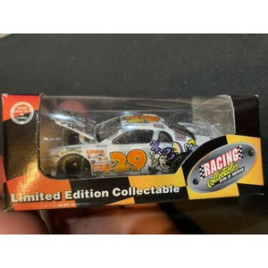 Op de afbeelding: Een witte die-cast auto met nummer 29 aan de zijkant. De auto bevindt zich in een doorzichtige plastic behuizing met een gele en zwarte achtergrond. De tekst "Racing Collectibles Club of America" staat op de achtergrond. De tekst "Limited Edition Collectible" staat op de voorkant van de behuizing.