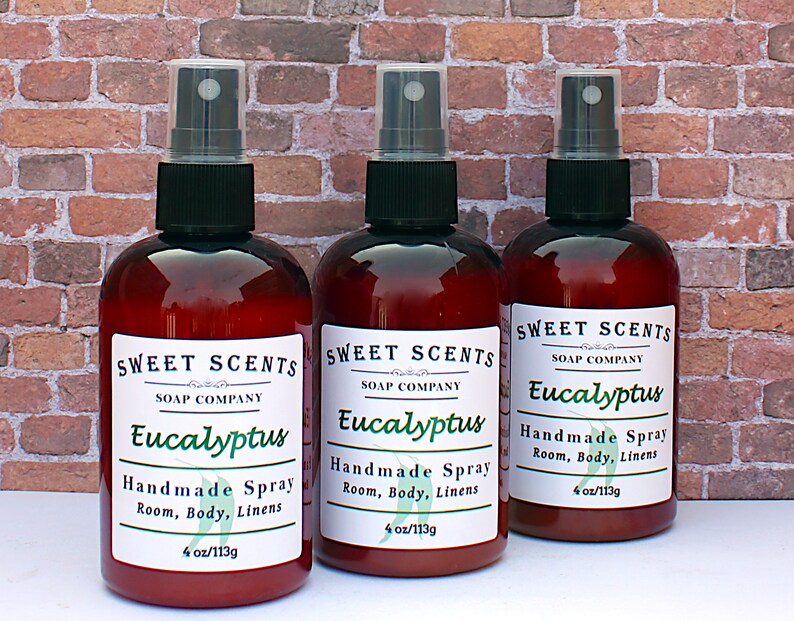 Pu&ograve; includere: Tre bottiglie di vetro marrone con spruzzini neri ed etichette bianche. Le etichette riportano "Sweet Scents Soap Company Eucalyptus Handmade Spray Room, Body, Linens 4 oz/113g".