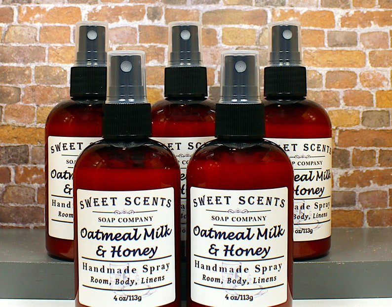May include: Six brown glass bottles with spray tops filled with a clear liquid. The bottles have white labels with black text that reads "Sweet Scents Soap Company Oatmeal Milk & Honey Handmade Spray Room, Body, Linens 4 oz/113g".
