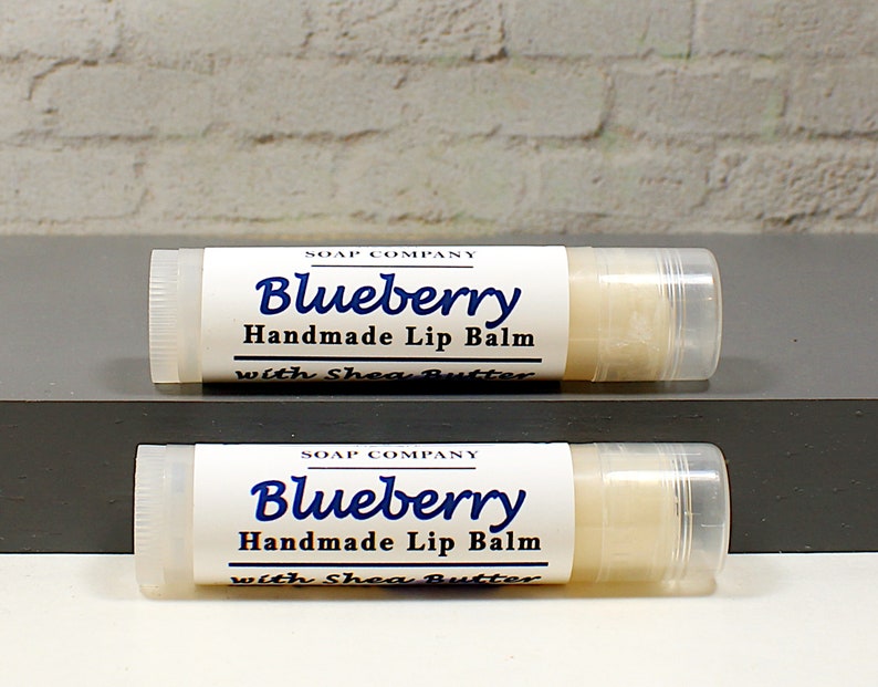 May include: Two tubes of handmade blueberry lip balm with shea butter. The labels are white with blue text that reads "Blueberry Handmade Lip Balm with Shea Butter". The lip balm is in a clear tube.
