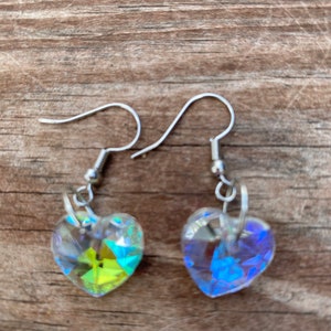 Könnte beinhalten: Ein Paar silberne herzförmige Ohrringe mit schimmernden Kristall-Akzenten. Die Ohrringe haben einen Hakenverschluss.