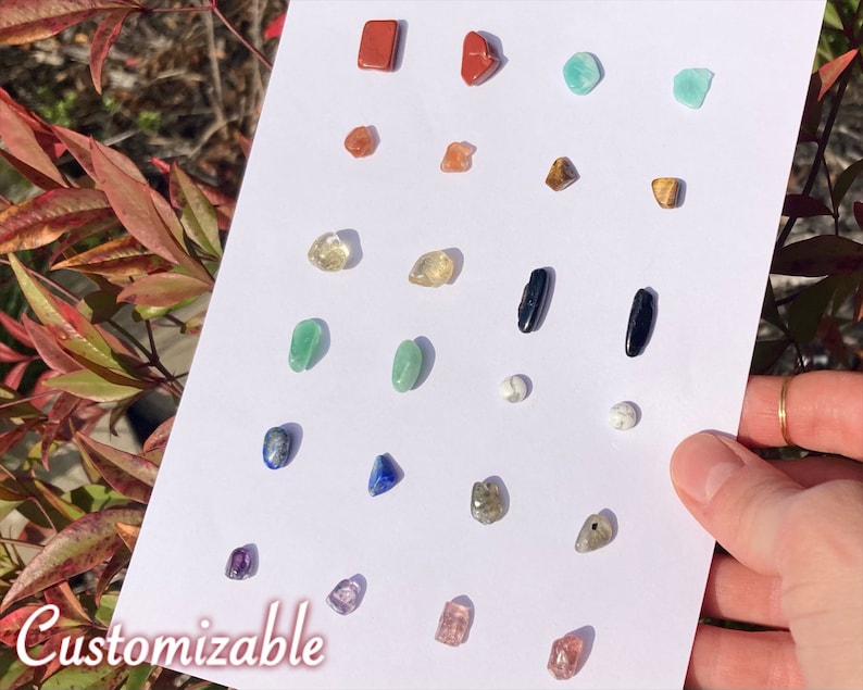 12 pairs of Crystal Stud Earrings on a large white card, a spectrum of rainbow & neutral tones: red jasper, carnelian, citrine, green aventurine, lapis lazuli, amethyst, amazonite, tigers eye, black tourmaline, howlite, labradorite, strawberry quartz