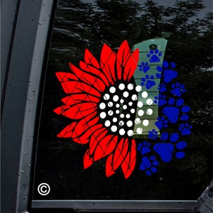 Puede incluir: Girasol rojo, blanco y azul con huellas de patas. El girasol es mitad rojo y mitad blanco con un centro blanco. Las huellas de patas son azules y llenan la otra mitad del girasol.