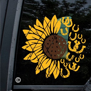 Puede incluir: Un girasol amarillo con un centro marrón, rodeado por un anillo de herraduras doradas. El girasol tiene un patrón de cuadros.