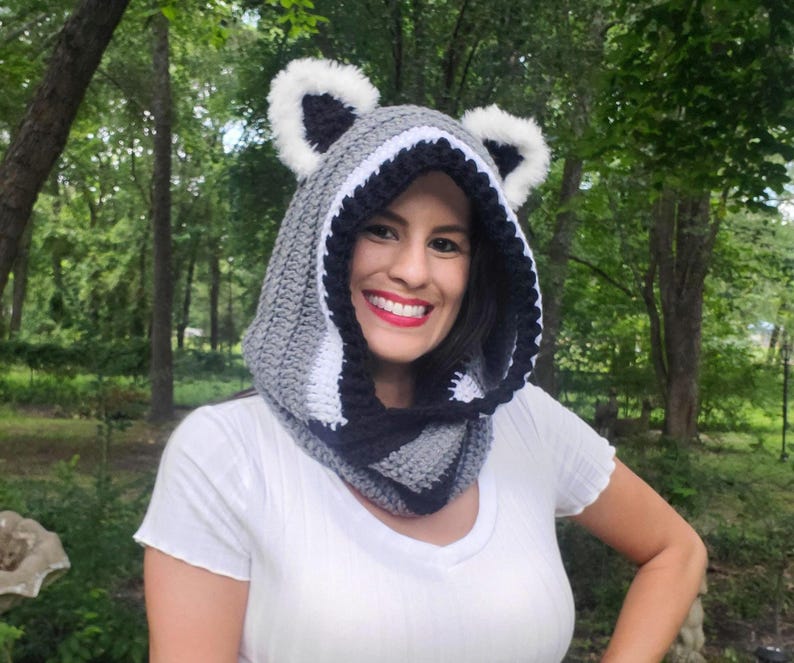 Puede incluir: Una capucha de ganchillo hecha a mano en gris, negro y blanco, con orejas de mapache. La capucha est&aacute; dise&ntilde;ada para usarse alrededor de la cabeza y el cuello. La capucha est&aacute; hecha de hilo suave y es adecuada para el clima fr&iacute;o.