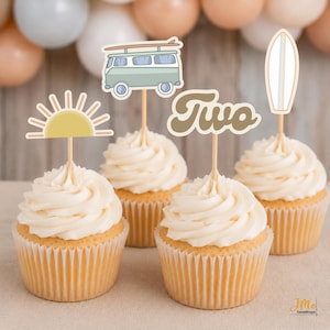 May include: Four cupcakes topped with decorative paper toppers featuring a yellow sun, a light green camper van with a surfboard, the word Two in brown script, and a white surfboard. Each topper is attached to a thin wooden pick.