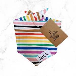 May include: Rainbow striped bandana with white snaps and a personalized name tag that says "Jack". The bandana is made by Moon Petals.