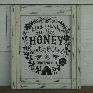 May include: A framed canvas sign with a black and white design of a beehive, bees, flowers, and the text "Kind words are like honey sweet to the soul Proverbs 16:24".
