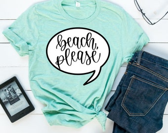 May include: A light blue t-shirt with a white speech bubble that says "beach, please" in black cursive lettering.