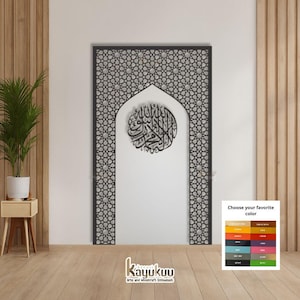 Peut inclure: Une œuvre d'art murale en bois découpé au laser noir, avec un cadre en forme d'arche et un motif géométrique. À l'intérieur de l'arche se trouve un motif circulaire avec de la calligraphie arabe. L'œuvre est affichée sur un mur blanc.