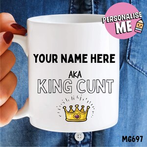 May include: White ceramic mug with a black and white design that says "YOUR NAME HERE AKA KING CUNT" with a gold crown with a purple jewel on top.