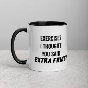May include: White ceramic mug with a black interior and handle. The mug features the text "EXERCISE? I THOUGHT YOU SAID EXTRA FRIES!" in black, bold font. The mug is designed for beverages.
