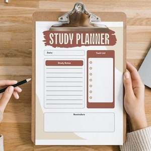 May include: A white study planner with a brown clipboard, a pencil, and a laptop on a wooden surface. The planner has the words "STUDY PLANNER" in brown text with a brown background. The planner has sections for "Date", "Study Notes", "Task List", and "Reminders".