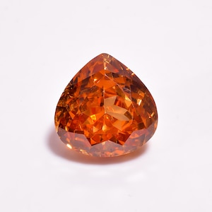 May include: A pear-shaped gemstone with a vibrant orange color and a faceted surface. The stone features a pointed top and a rounded base, reflecting light through its numerous cut angles to create a bright, translucent appearance.