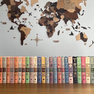 May include: A collection of vintage hardback books with colourful spines and illustrations. The books are arranged in a row on a wooden surface.