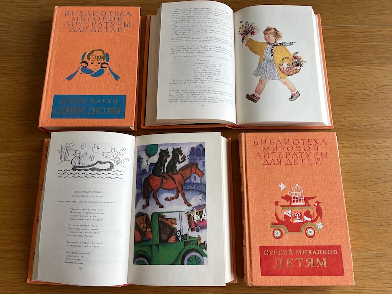 May include: Three orange hardback books with the title "Bibliotheca Mirovoi Literatury Dlya Detey" on the front cover. The first book has the text "Takhi Detyam" on the front cover. The second book has a black and white illustration of a girl in a yellow dress holding a basket. The third book has a black and white illustration of a car with animals inside.