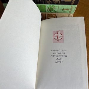 May include: A white book with a red logo and the text "Biblioteca мировой литературы для детей" on the cover.