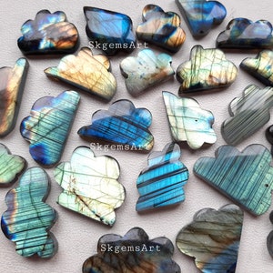Könnte beinhalten: Eine Sammlung von 18 regenbogenfarbenen Labradorit-Cabochons, die jeweils in Form einer Wolke geschnitzt sind. Die Steine haben eine Vielzahl von Farben, darunter Blau, Grün und Gold.
