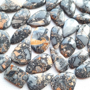 May include: A collection of 20+ natural gemstone cabochons in a teardrop shape. The stones are a mix of black, gray, and brown with gold flecks. The cabochons are polished and ready to be used in jewelry making.
