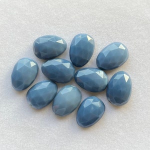 Könnte beinhalten: Zehn glatte, ovale blaue Opal-Steine. Die Steine sind facettiert und haben eine hellblaue Farbe.
