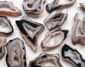 May include: A collection of 12 agate slices, each with a unique shape and size. The agate slices are translucent and feature a natural, earthy colour palette of brown, white, and black. The agate slices have a distinctive, crystal-like appearance.
