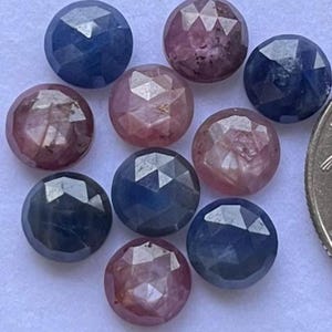 Peut inclure: Un ensemble de pierres précieuses facettées dans des tons de bleu et de rose. Les pierres rondes présentent une taille géométrique, reflétant la lumière. Les pierres précieuses sont disposées de près, mettant en valeur leurs variations de couleurs et leur brillance.