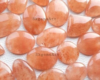 May include: A collection of 15 orange and red carnelian cabochons with a variety of shapes and sizes. The stones are translucent and have a natural, organic look. SkgemsArt is printed on two of the stones.