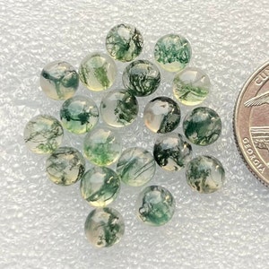 May include: A collection of 18 moss agate cabochons, each with a unique green and white pattern. The cabochons are round and smooth, and they are approximately 1/2 inch in diameter.