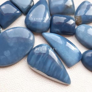 May include: A collection of blue opal cabochons in various shapes and sizes. The opals have a milky blue color with some showing a hint of iridescence.