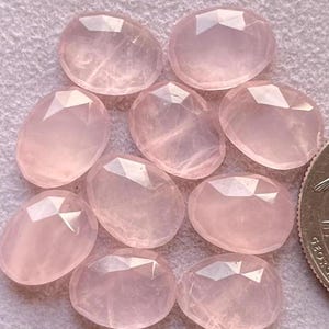 Könnte beinhalten: Neun ovale geschliffene Rosenquarzsteine. Die Steine sind hellrosa und durchscheinend.