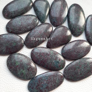 May include: A collection of 12 oval-shaped green and red gemstone cabochons. The stones have a mottled, speckled appearance.  SkgemsArt.