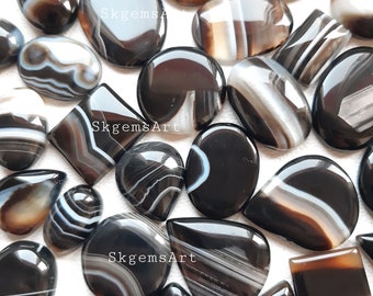 May include: A collection of 20 black and white agate cabochons, featuring various shapes and sizes. The cabochons have a polished, smooth surface and display intricate banding patterns.