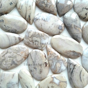 以下が含まれることがあります： 様々な形と大きさの15個の天然石カボションのセットです。石は薄いベージュ色で、茶色と灰色の渦巻き模様とパターンがあります。石は研磨されており、滑らかで光沢のある仕上がりです。