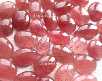 May include: A collection of 20 oval and teardrop shaped, translucent, pink, rose quartz cabochons. The stones have a speckled, cloudy appearance.