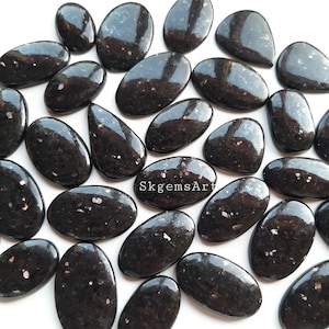 Op de afbeelding: Een verzameling van 20 zwarte edelsteen cabochons met een glinsterende, iriserende afwerking. De cabochons zijn ovaalvormig en hebben een glad, gepolijst oppervlak.